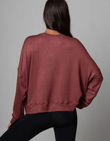 woman wearing relaxed and boxy reddish brown earthy colored pullover on grey background