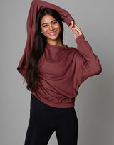 woman wearing relaxed and boxy reddish brown earthy colored pullover on grey background