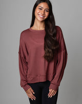 woman wearing relaxed and boxy reddish brown earthy colored pullover on grey background
