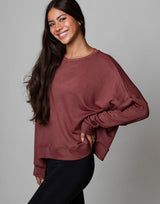 woman wearing relaxed and boxy reddish brown earthy colored pullover on grey background