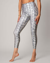 Person wearing silver snake print leggings on a gray background
