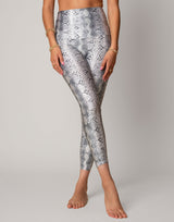 Person wearing silver snake print leggings on a plain background