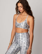 woman wearing white python printed sports bra on grey background
