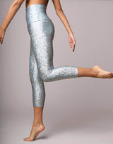 woman wearing legging with mermaid pattern of crystal blue colored sparkling fish scales on grey background