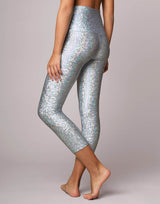 woman wearing legging with mermaid pattern of crystal blue colored sparkling fish scales on grey background
