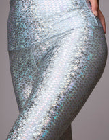 woman wearing legging with mermaid pattern of crystal blue colored sparkling fish scales on grey background