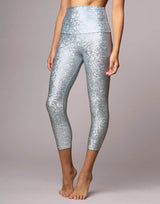 woman wearing legging with mermaid pattern of crystal blue colored sparkling fish scales on grey background