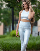 woman wearing long legging with mermaid pattern of crystal blue colored sparkling fish scales outdoors