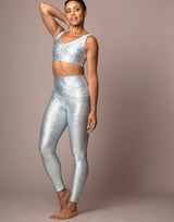 woman wearing v neck crop top and legging set with mermaid pattern of crystal blue colored sparkling fish scales on grey background