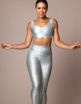 woman wearing long legging with mermaid pattern of crystal blue colored sparkling fish scales on grey background