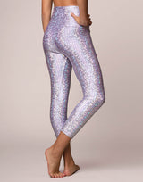woman wearing legging with mermaid pattern of lavender purple colored sparkling fish scales on grey background