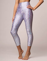 woman wearing legging with mermaid pattern of lavender purple colored sparkling fish scales on grey background
