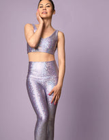 woman wearing long legging with mermaid pattern of lavender purple colored sparkling fish scales on lilac background