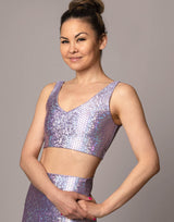 woman wearing v neck crop top with mermaid pattern of lavender purple colored sparkling fish scales on grey background