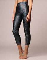 woman wearing legging with mermaid pattern of midnight black colored sparkling fish scales on grey background