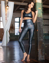 woman wearing sports bra and legging with mermaid pattern of midnight black colored sparkling fish scales in a studio