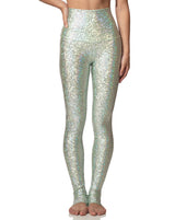 woman wearing long legging with mermaid pattern of mint colored sparkling fish scales on grey background