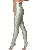 woman wearing long legging with mermaid pattern of mint colored sparkling fish scales on grey background