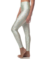 woman wearing sneaker length legging with mermaid pattern of mint colored sparkling fish scales on grey background