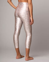 woman wearing legging with mermaid pattern of pink colored sparkling fish scales on grey background