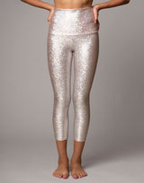 woman wearing legging with mermaid pattern of pink colored sparkling fish scales on grey background