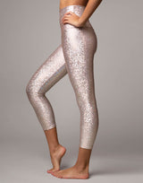 woman wearing legging with mermaid pattern of pink colored sparkling fish scales on grey background