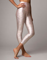 woman wearing legging with mermaid pattern of pink colored sparkling fish scales on grey background