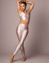 woman wearing v neck crop top with mermaid pattern of pink colored sparkling fish scales on grey background