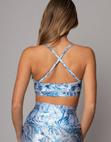 Woman wearing a blue floral sports bra and leggings set on a gray background