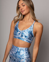 Woman wearing a blue floral sports bra and leggings set against a gray background