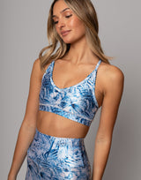 Woman wearing a blue floral sports bra and leggings on a gray background