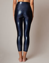 Person wearing shiny blue leggings on a neutral background