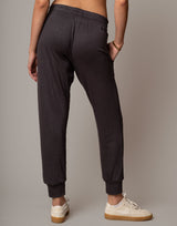 Person wearing dark gray sweatpants with a neutral background