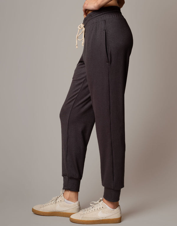 Dark jogger pants worn by a person on a plain background