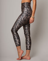 Person wearing black and silver patterned leggings on a plain background