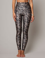 Person wearing black and gray patterned leggings on a plain background