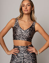 Woman wearing a patterned sports bra and leggings against a neutral background