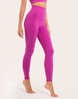 A model wearing high-waisted magenta pink leggings and a matching sports bra, shown from the waist down against a plain white studio background.