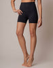 A model wearing high-waisted black athletic shorts against a solid light beige studio background.