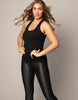 Woman wearing a black tank top and black leggings against a neutral background