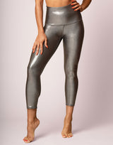 Person wearing shiny silver leggings on a light pink background