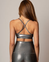 Person wearing a metallic silver strappy top and high-waisted leggings against a neutral background