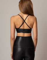 Person wearing a black shimmer outfit with criss-cross straps on a neutral background