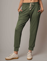 Person wearing olive green jogger pants with a plain background