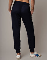 Person wearing black jogger pants with white sneakers on a neutral background