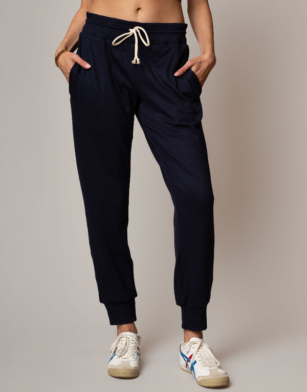 Person wearing navy jogger pants with a plain background