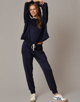 Woman wearing a navy tracksuit with white sneakers on a plain background