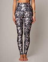 Person wearing black and white floral leggings on a plain background