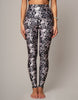 Person wearing black and white floral leggings on a plain background