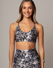 Woman wearing a black and white floral sports bra and leggings on a gray background